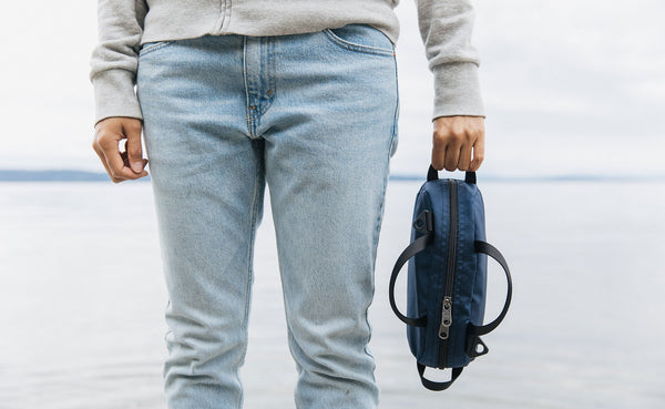 A person holding a Navy Parapack Grab Bag by it's end handle at the beach.
